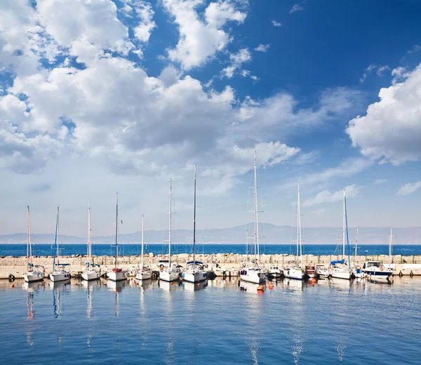 Barcos de vela y pesca en un puerto bajo un cielo nublado — Foto de Stock