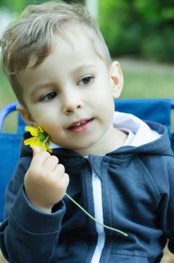 Doğayı seven çocuk. Küçük bir çocuk elinde bir çiçek tutuyor. Düşünceli çocuk. Çocukların duyguları.