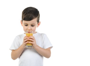 6 yaşında beyaz tişörtlü bir çocuk beyaz arka planda narenciye suyu içiyor. Tecrit edilmiş arka plan, çocuklar için sağlıklı yiyecekler, okul çocukları...