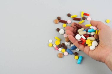 Gri arka planda haplar bir kadının avucundan düşer. Sağlık hizmeti konsepti. COVID-19; Coronavirus; Tedavi; Virüs; Boşluğu Kopyala