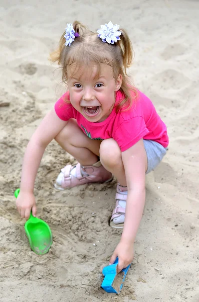 Hermosa niña jugando en una caja de arena, una foto de cerca . — Foto de Stock