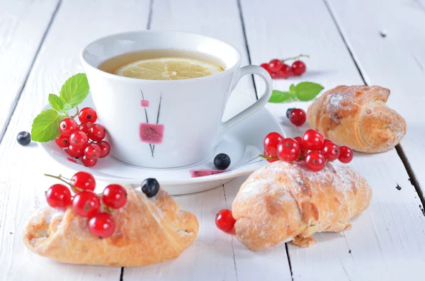 Ранковий чай, ягоди червоної смородини та круасани на дерев'яній тарілці — стокове фото