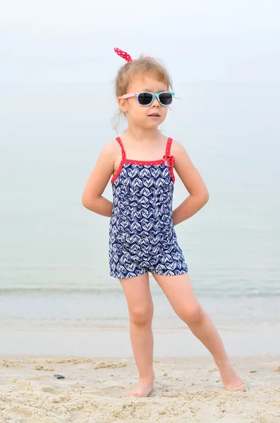 Charmig liten flicka i en baddräkt och solglasögon poserar på — Stockfoto