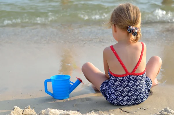 Vacker liten flicka spelar på stranden. — Stockfoto