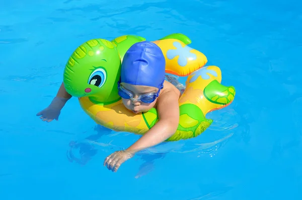 Un niño pequeño nada en la piscina, gafas, gorra de natación . — Foto de Stock