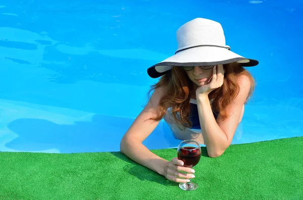 Hermosa mujer joven en un sombrero y gafas de sol en el borde de la — Foto de Stock