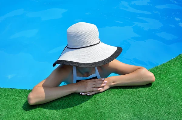 Ung kvinne med solhatt i bassenget, flott utsikt . – stockfoto