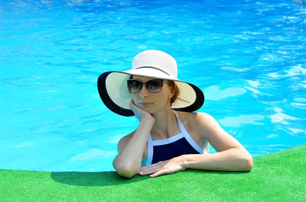 Hermosa mujer joven en un sombrero de sol y gafas de sol en el borde de la caca — Foto de Stock