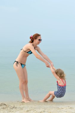 Aile, anne ve kızı kumsalda oynarken.