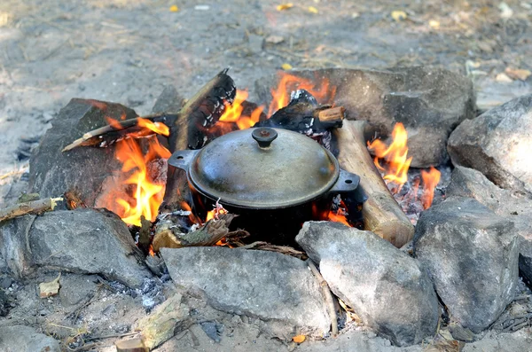 Cozinhar comida em uma panela de ferro fundido sobre uma fogueira aberta, caminhadas . — Fotografia de Stock