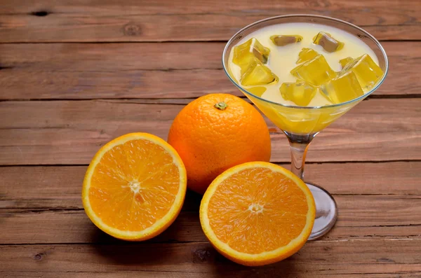 Χυμό πορτοκάλι με παγάκια σε ένα ποτήρι μαρτίνι σε ένα ξύλινο τραπέζι. — Φωτογραφία Αρχείου