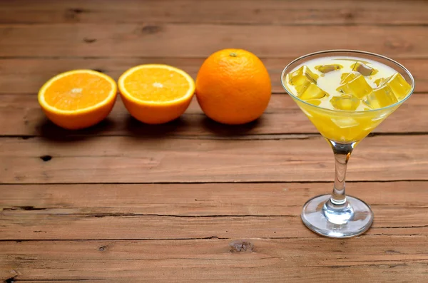 A glass of fresh orange juice with ice cubes on brown wooden bac — Stock Photo, Image