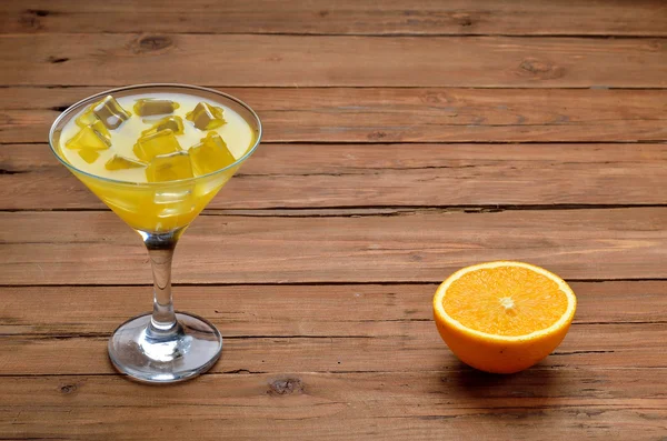 Orange juice with ice in a glass of martini on a wooden table. — Stock Photo, Image