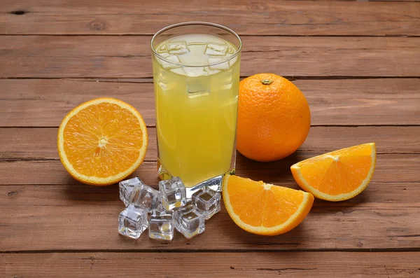 Szklance świeżego soku pomarańczowego i pomarańcze na starym drewnianym stole — Zdjęcie stockowe