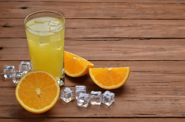 A glass of fresh orange juice and oranges on an old wooden table — Stock Photo, Image