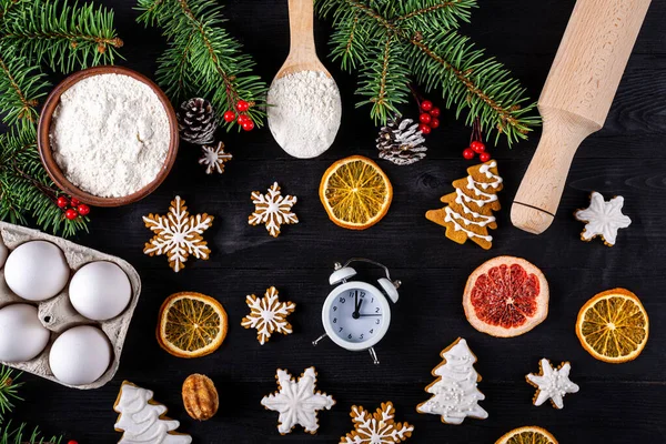 Christmas cookies and ingredients for their preparation on a wooden table top view. Xmas background.