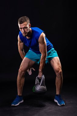 Siyah arka planda ağırlık kaldırma antrenmanı. Kettlebell ile Fitness.