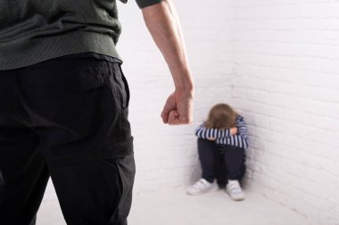 Köşede korkmuş küçük bir kız oturuyor. Aile içi şiddet. Çocuk istismarı.