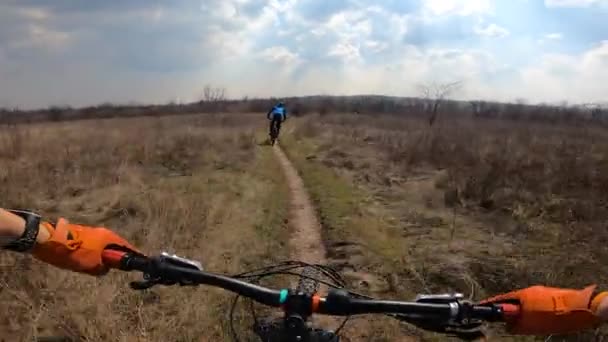 两个骑自行车的人骑着马穿过田野.从第一个人那里. — 图库视频影像