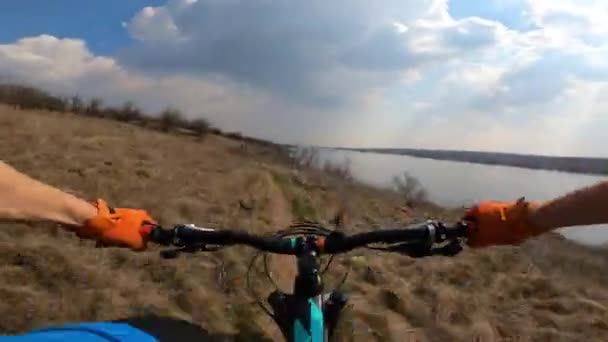 Велосипедист їде технічною стежкою вздовж річки. Перегляд від першої особи . — стокове відео