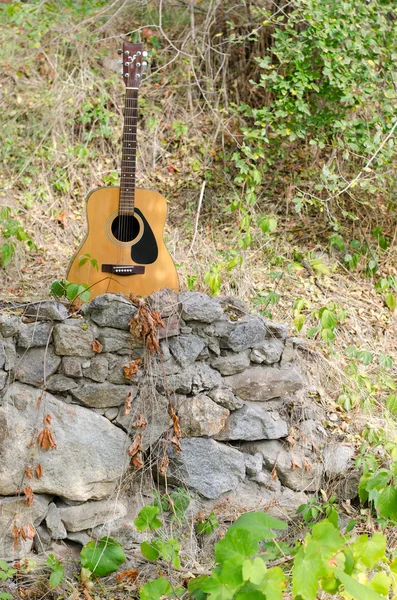 Guitarra acústica en un rock — Foto de Stock