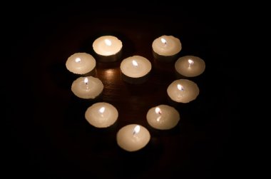 siyah arka plan üzerinde kalp şeklinde yanan mumlar