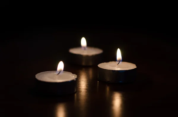 Three burning candles on black background — Stock Photo, Image