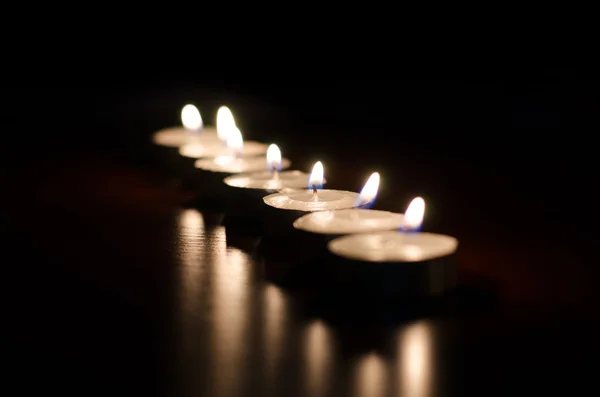 Línea de velas encendidas sobre fondo negro —  Fotos de Stock