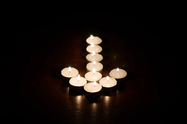 Burning candles in the shape of an arrow on a black background — Stock Photo, Image