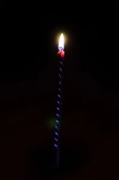 Высокая горящая свеча на черном фоне — стоковое фото