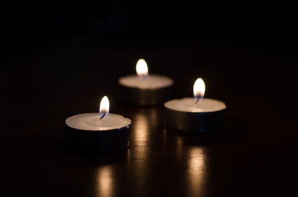 Three burning candles on black background