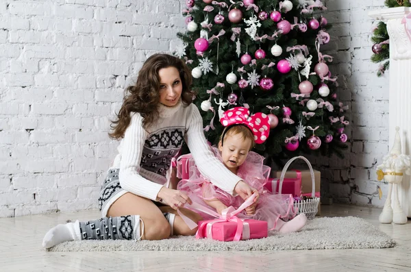 Mom and daughter unpack a gift near the Christmas tree — Stock Photo, Image