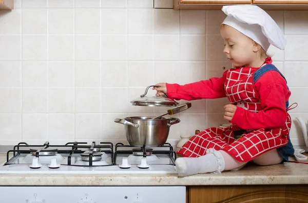 Little cook opens the pan with food — Stock Photo, Image