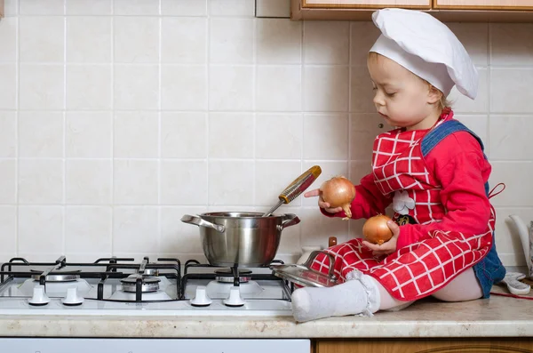 Pequeno chef coloca no pote legumes — Fotografia de Stock
