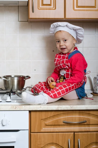 Pequeno cozinheiro limpa cebola — Fotografia de Stock