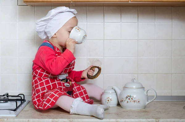 En liten baker som drikker te med bagels – stockfoto