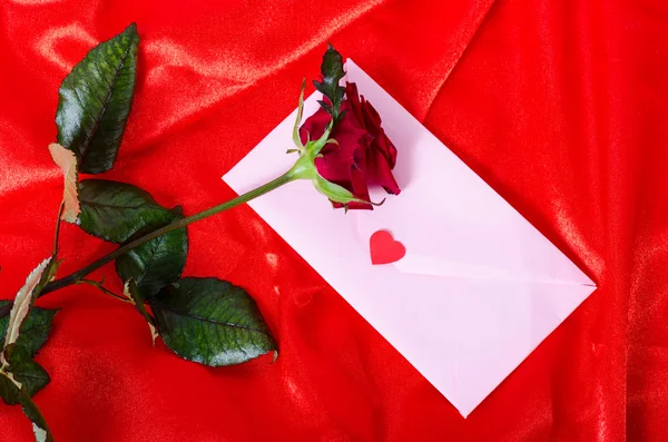 Red rose on satin cloth, an envelope with a wish — Stock Photo, Image