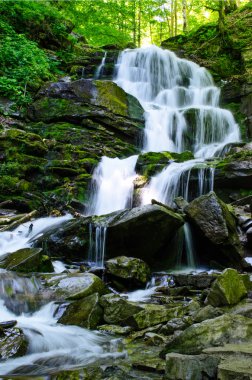 Landscape with a beautiful waterfall and a mountain river in the