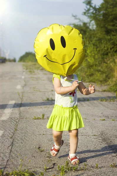 Un niño con un globo en forma de sonriente — Foto de Stock