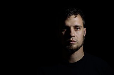 Siyah bir arka plan karşı bir sakallı bir adam portresi.