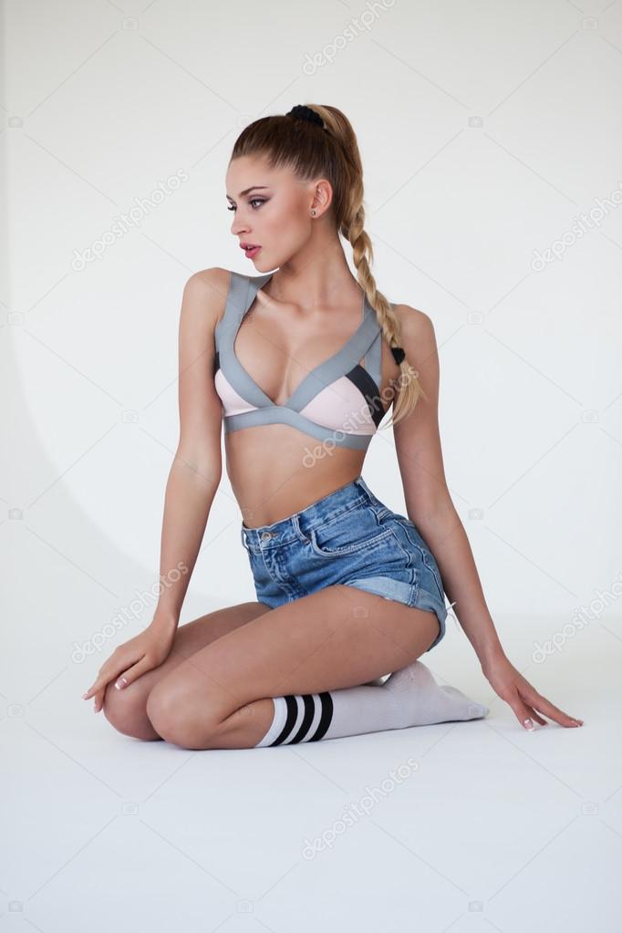 Sexy woman in shorts, gaiters and lingerie on a gray gradient