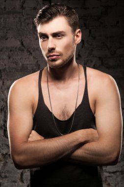 Duvarın yanında siyah bir tişört ayakta yakışıklı kaslı adam