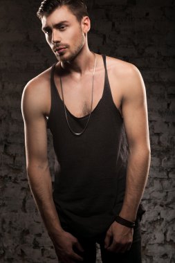Duvarın yanında siyah bir tişört ayakta yakışıklı kaslı adam