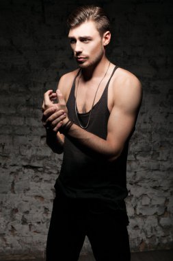 Duvarın yanında siyah bir tişört ayakta yakışıklı kaslı adam