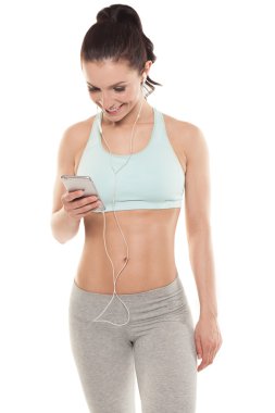 Fitness kız beyaz bir arka plan üzerinde bir akıllı telefon ile hoşlanır spo