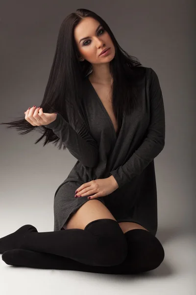 Fashion shot of a beautiful sexy brunette woman with long straight hair, in a jacket and stockings