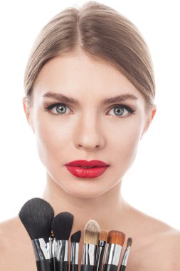 Makyaj fırçaları yanında çekici yüzü ile güzel bir kadın portresi. Yetişkin kız beyaz arka plan üzerinde poz