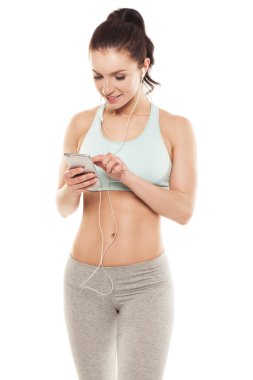 Beyaz arka planda akıllı telefonu olan fitness kızı spor antrenmanlarını, spor antrenmanlarını seviyor.