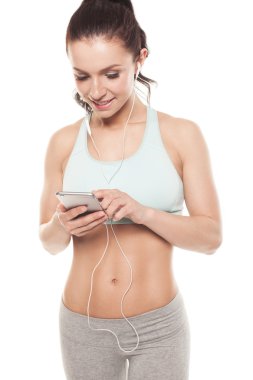 Beyaz arka planda akıllı telefonu olan fitness kızı spor antrenmanlarını, spor antrenmanlarını seviyor.