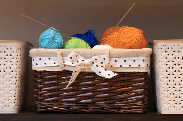 Birçok renkli yün iplikler ve örgü iğneleri dikiş sepetinde bulunur..